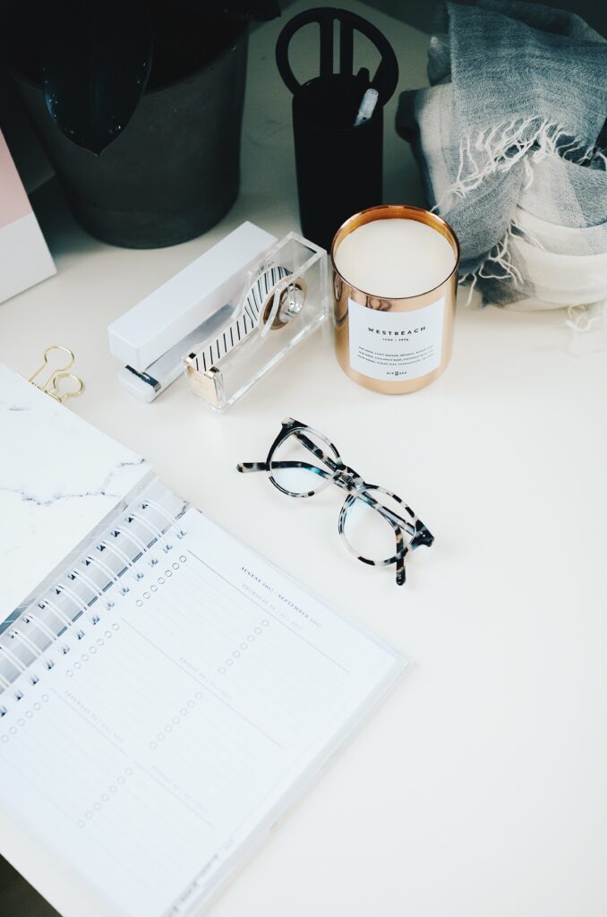 Planner, glasses and candle on desk